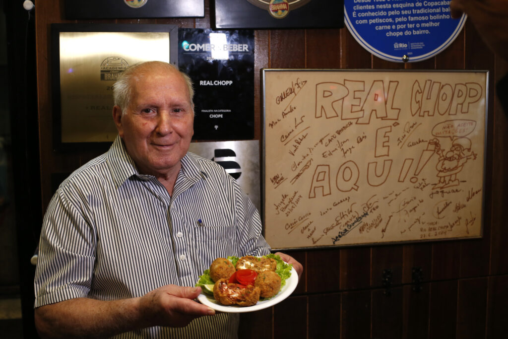 Sr. Herminio segura baixela com dose dupla de bolinhos de carne seca e de costela recheados com queijo cremoso
